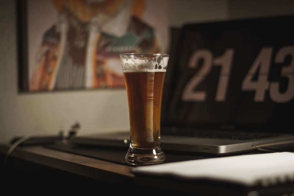 Glas Bier auf einem Tisch, im Hintergrund eine Uhr